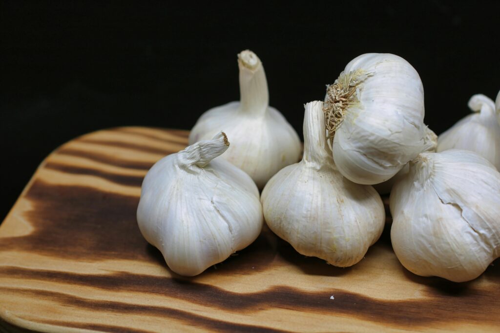 Fresh garlic bulbs placed on a wooden board with a black background, perfect for culinary themes.